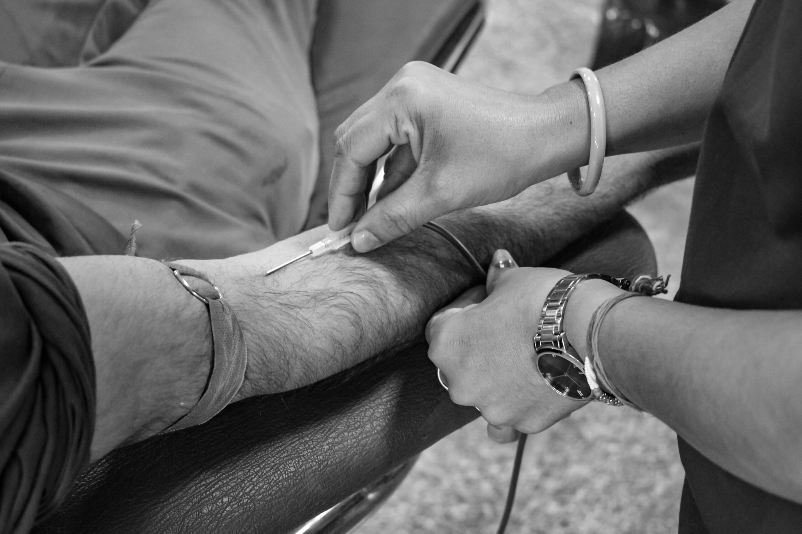 Older adult receiving medical care with a near-infrared vein visualization device helping a clinician locate a vein.