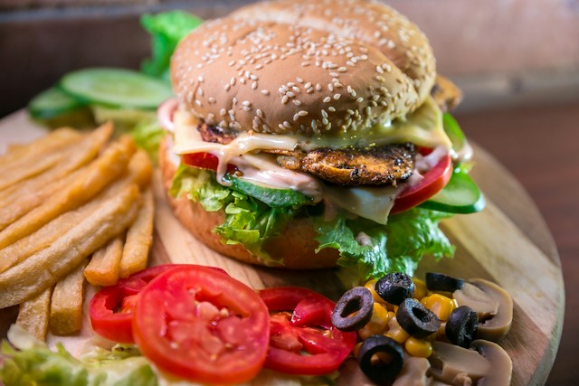 Older adult choosing between a fast-food meal and a varied plate of vegetables, whole grains and protein