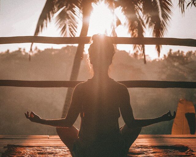 Person practicing loving-kindness meditation outdoors in a peaceful setting