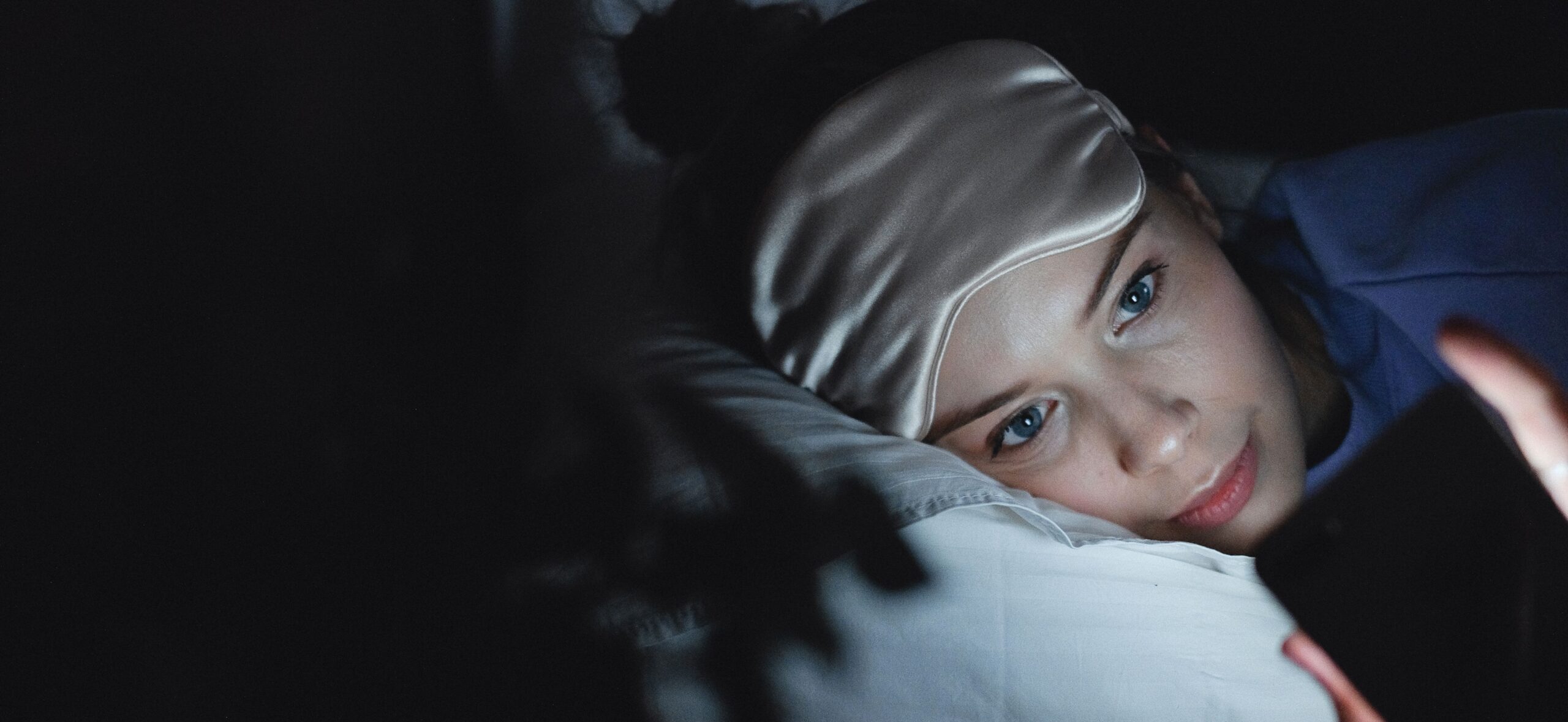 Older adult sleeping in a bedroom with curtains blocking outdoor light and a dim nighttime pathway light