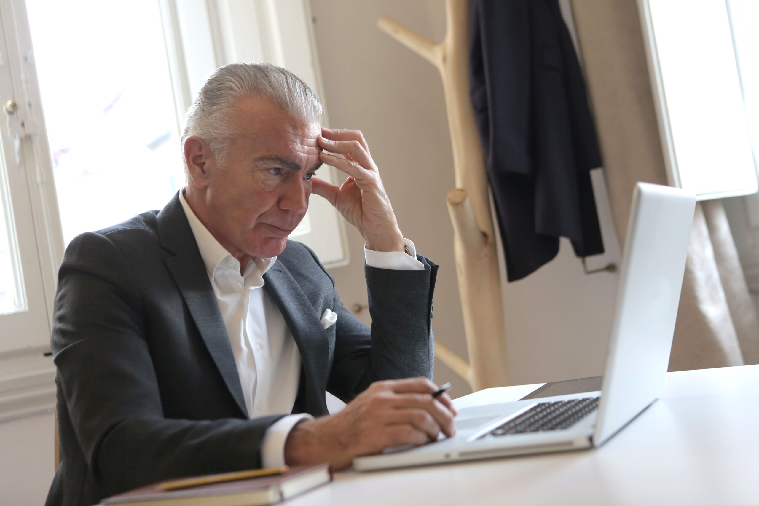 Older employee sitting thoughtfully at a desk after a stressful workplace interaction, representing the impact of workplace stress on mental health.