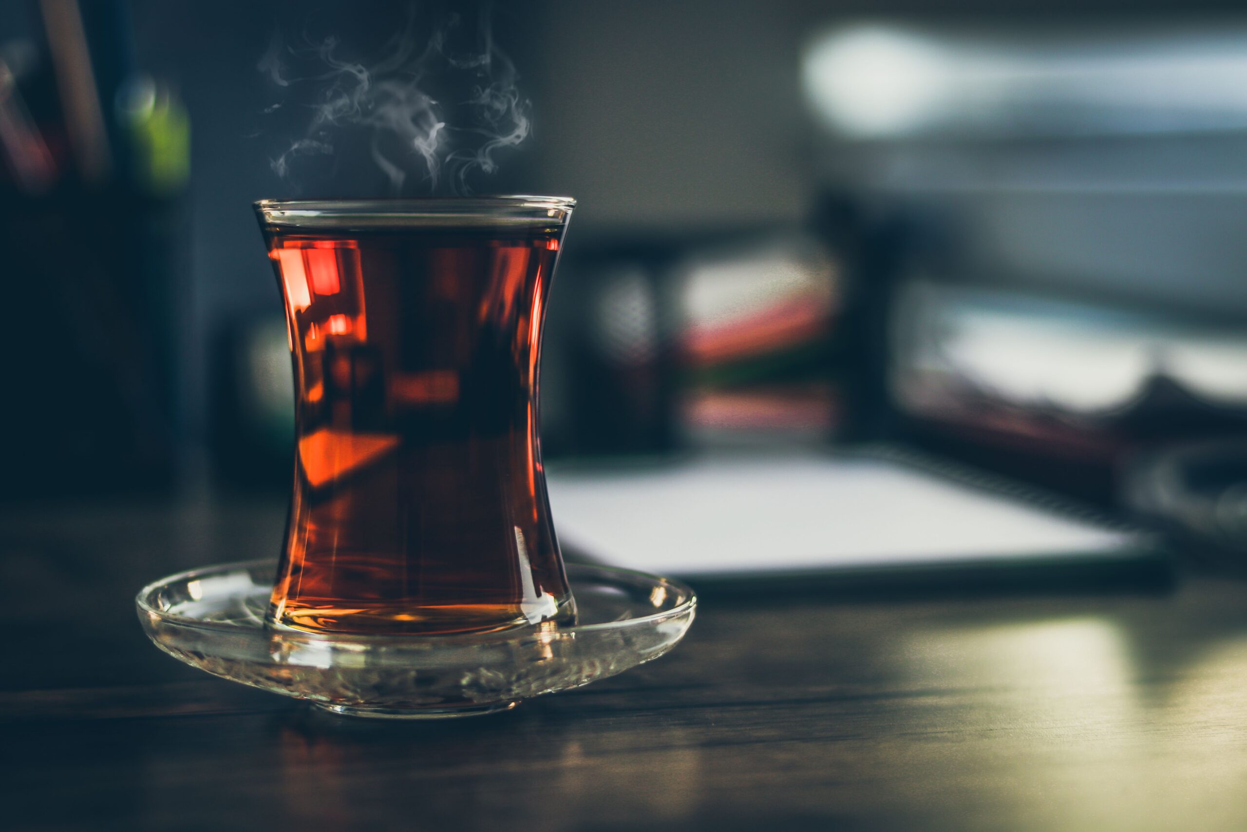Older adult holding a steaming cup of tea while considering the health effects of very hot beverages.