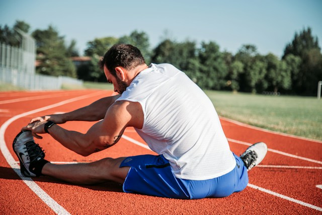 Adult performing a gentle full-body stretch beside a chair to improve flexibility and ease stiffness after sitting.