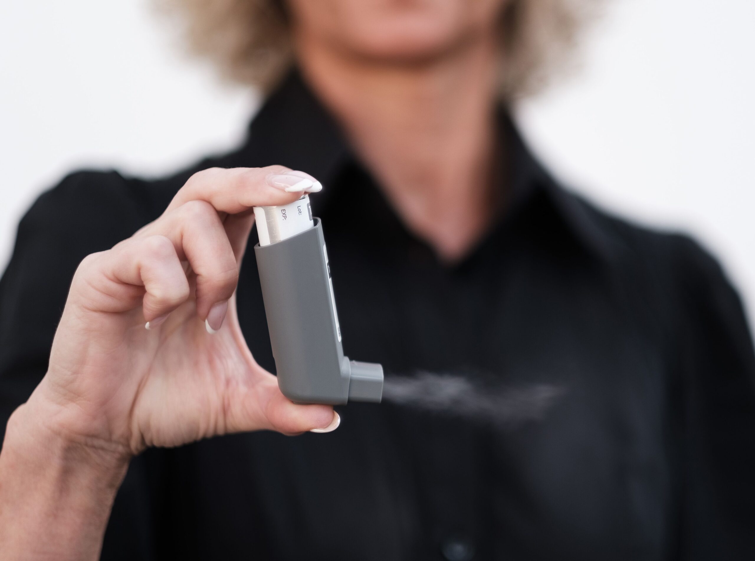 A child using an asthma inhaler with a spacer under adult supervision.